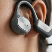 Black waterproof bone conduction headphones resting on a sleek surface with water droplets.