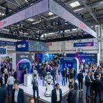 Packed exhibition hall at DMEXCO 2026 in Cologne's Koelnmesse, with visitors exploring digital marketing and technology stands under bright overhead lighting