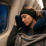 A passenger sleeping comfortably on a plane wearing soft sleep headphones.