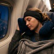 A passenger sleeping comfortably on a plane wearing soft sleep headphones.