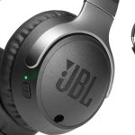 Black JBL wireless over ear headphones on a sleek desk surface.