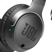 Black JBL wireless over ear headphones on a sleek desk surface.